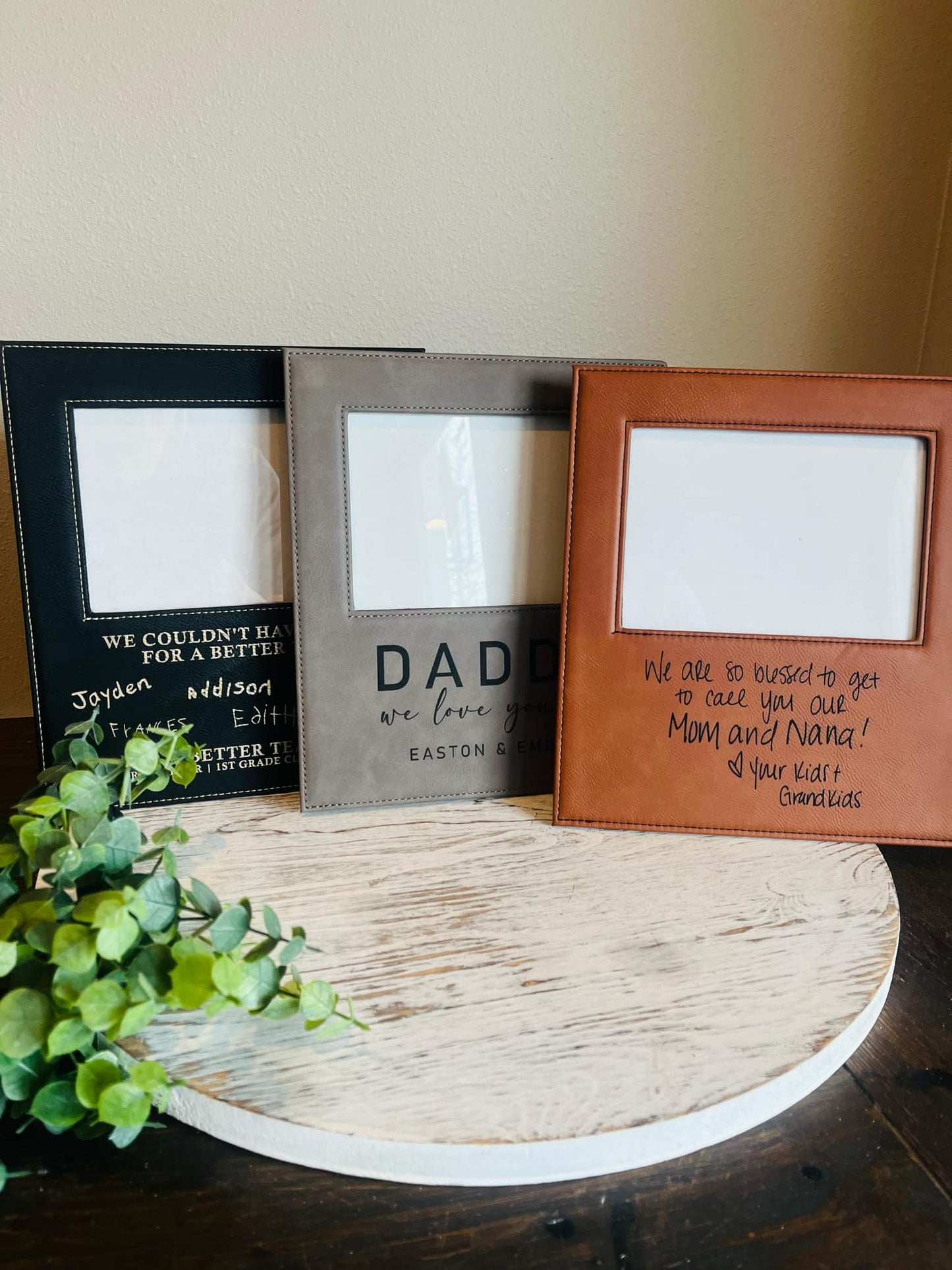 A variety of 3 photo frames - one showing the black leather frame that engraves silver, the grey leather frame that engraves black and the brown leather frame that engraves black.